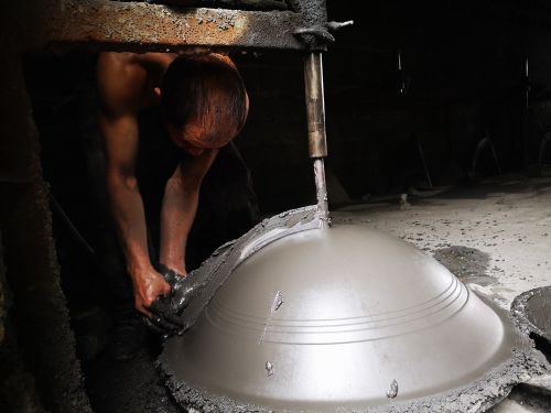 工人正在制作光滑的铁锅模子。