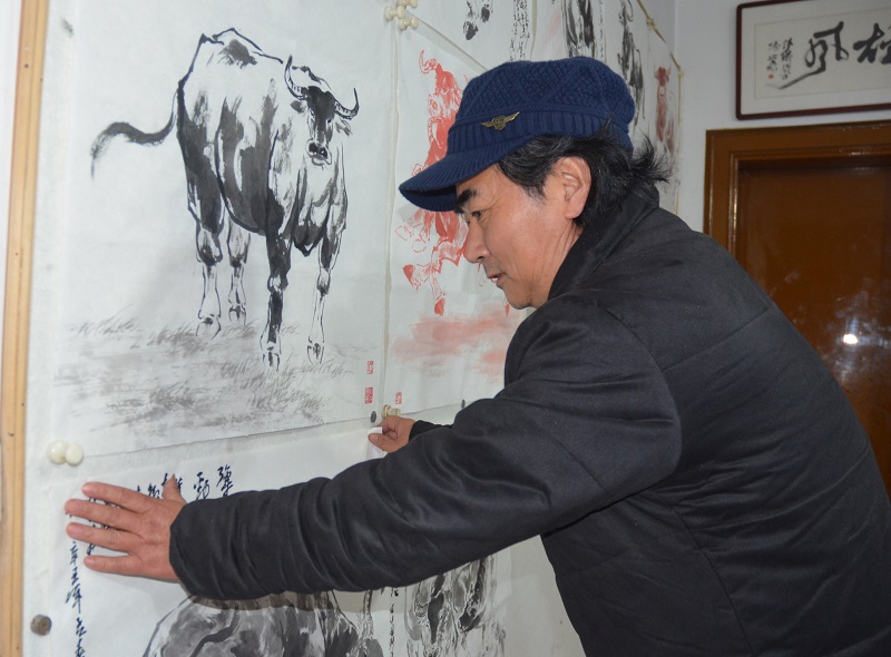 吕伟杰悬挂”牛“画作品上墙。