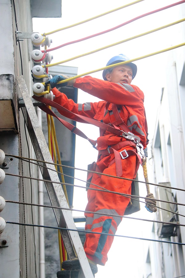 2021年5月4日，一名施工队员在加勉乡政府驻地街道，对电线线路进行布线。