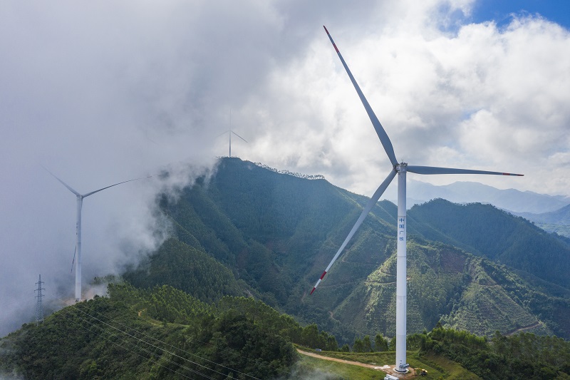10、2021年9月25日，在广西梧州岑溪市大隆镇东南一带山脊上的中广核风电场现场，青山叠翠，15台风力发电机组与云雾、乡村相映成景，构成了一道美丽的绿色画卷。（何华文）