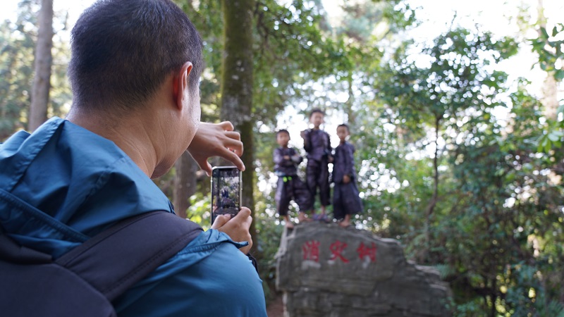 2021年10月5日，从江县丙妹镇岜沙景区内，一名游客正在拍摄当地苗族群众。