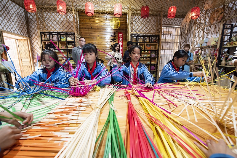 1、2021年11月25日，在广西梧州岑溪市市南渡镇中心小学，学生在老师的辅导下练习非遗竹芒编织手工技艺。（何华文）