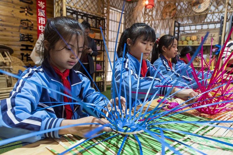 2、2021年11月25日，在广西梧州岑溪市市南渡镇中心小学，学生在老师的辅导下练习非遗竹芒编织手工技艺。（何华文）