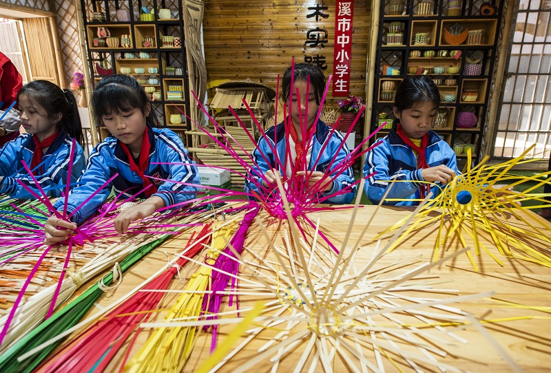 3、2021年11月25日，在广西梧州岑溪市市南渡镇中心小学，学生在老师的辅导下练习非遗竹芒编织手工技艺。（何华文）