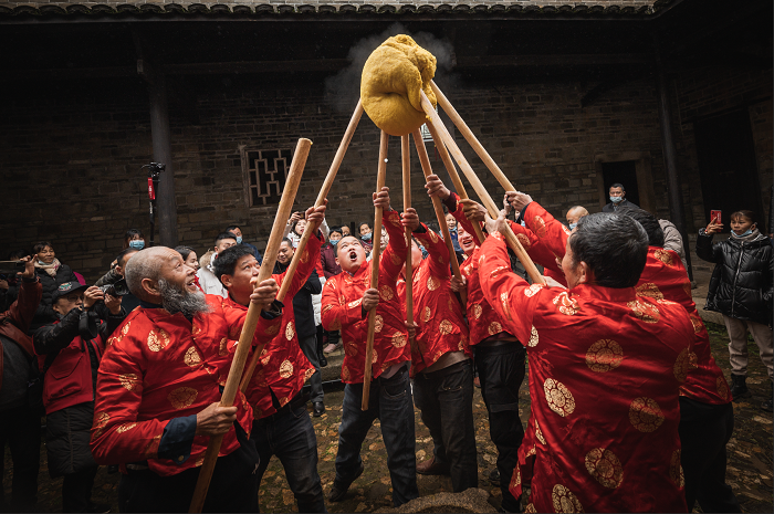 众人一起打黄元米果，是村里春节的盛事。