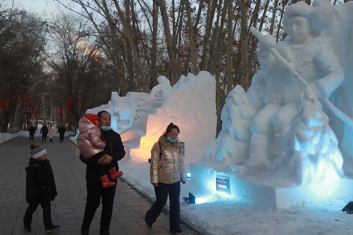 游人从雪雕旁走过