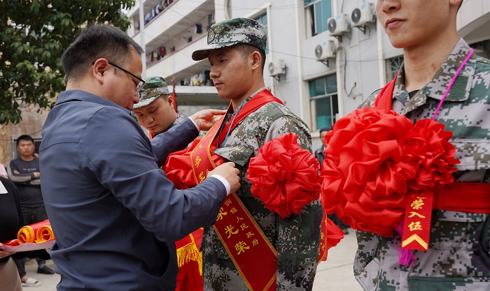 2022年3月14日，在贵州省黔东南苗族侗族自治州从江县停洞镇，工作人员正在为入伍新兵佩戴胸花和整理绶带。 (2)