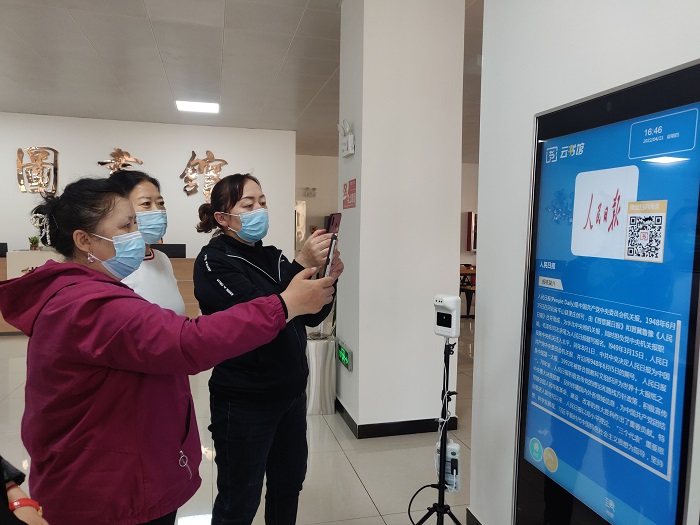 图为4月21日，福海县图书馆的工作人员指导读者利用“云书馆”“智能听书机”免费读书、听书。1