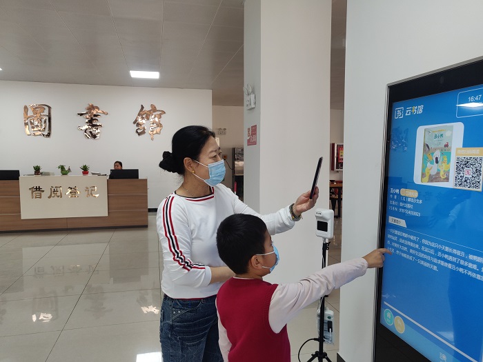 图为4月21日，福海县图书馆的工作人员指导读者利用“云书馆”“智能听书机”免费读书、听书。2