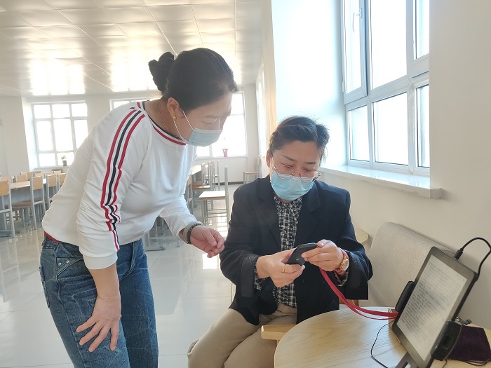 图为4月21日，福海县图书馆的工作人员指导读者利用“云书馆”“智能听书机”免费读书、听书。3