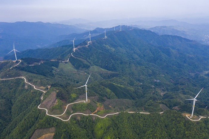 6、2022年5月19日，广西梧州市苍梧县六堡镇润堡风电场，一座座风力发电机组矗立山脊之上迎风旋转，与绿色群山、民居、村道相映成趣，美如画卷。（何华文）