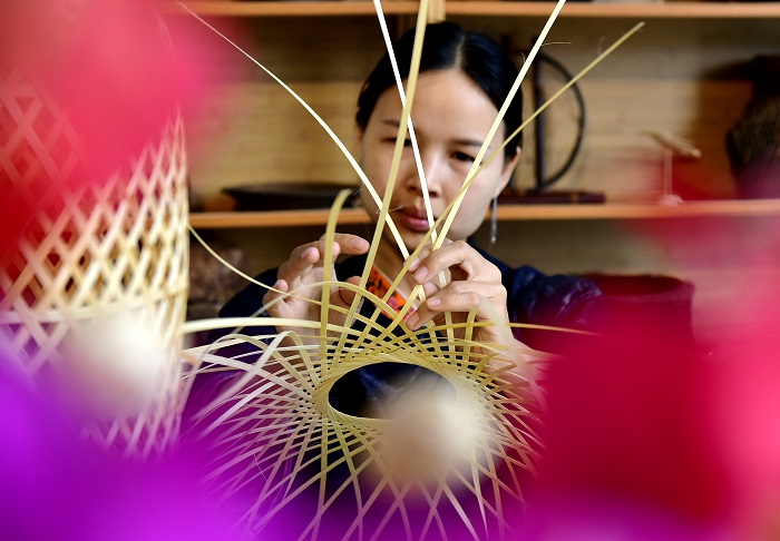 2022年5月21日，一名侗族妇女在贵州省黔东南苗族侗族自治州从江县銮里风情园一家竹编作坊编制传统手工艺品。（龙梦前 摄）2