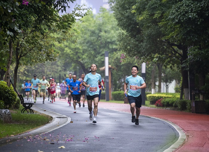 1、2022年5月22日，在广西梧州市玫瑰湖公园的步道上，梧州市畅跑跑步俱乐部会员冒雨参加运动趣味接力赛。（何华文）