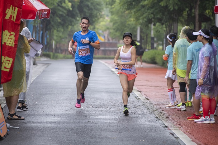 5、2022年5月22日，在广西梧州市玫瑰湖公园的步道上，梧州市畅跑跑步俱乐部会员冒雨参加运动趣味接力赛。（何华文）