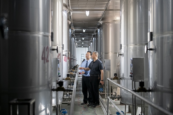 5、2022年5月24日，在广西梧州龙山酒业有限公司车间，国家税务总局梧州市税务局工作人员向企业负责人了解企业生产经营情况。（何华文）