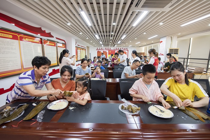 1、2022年5月28日，在广西梧州市青少年宫，孩子们在家长指导下学包粽子，迎接端午节的到来。（何华文）