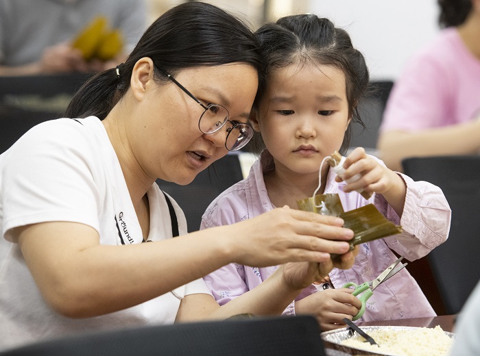4、2022年5月28日，在广西梧州市青少年宫，孩子们在家长指导下学包粽子，迎接端午节的到来。（何华文）