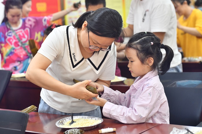 7、2022年5月28日，在广西梧州市青少年宫，孩子们在家长指导下学包粽子，迎接端午节的到来。（何华文）