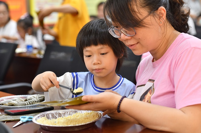 9、2022年5月28日，在广西梧州市青少年宫，孩子们在家长指导下学包粽子，迎接端午节的到来。（何华文）