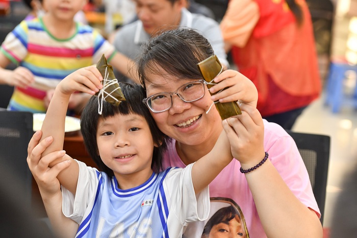 10、2022年5月28日，在广西梧州市青少年宫，孩子们在家长指导下学包粽子，迎接端午节的到来。（何华文）