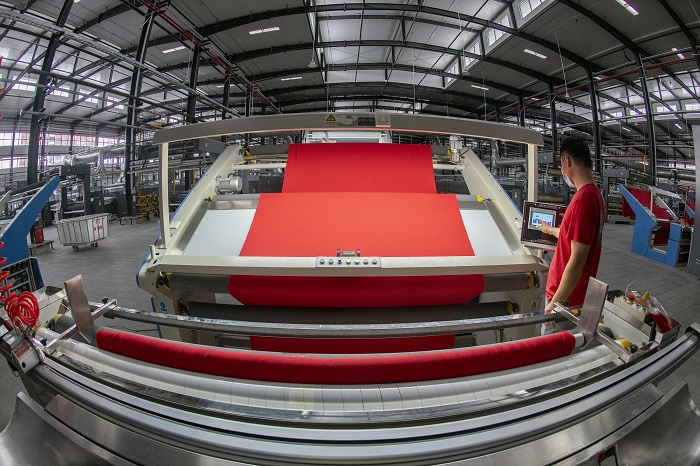 1、2022年5月31日，广西梧州岑溪市大业镇的泰森新纺织产业集聚区一期项目试投产，工人正在5号车间忙碌着，各种染整智能生产线正开足马力作业。（何华文）