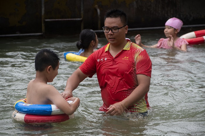 3、2022年7月17日，广西梧州市（桂江一桥边）游泳场内，孩子们在教练的指导下学习游泳技能。（何华文）