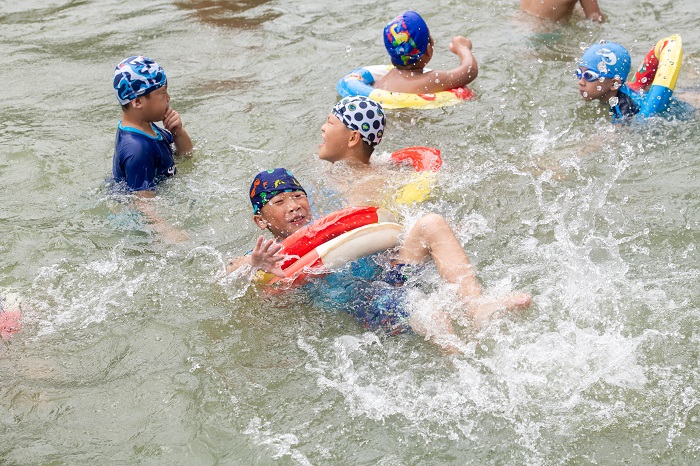 8、2022年7月17日，广西梧州市（桂江一桥边）游泳场内，孩子们在教练的指导下学习游泳技能。（何华文）