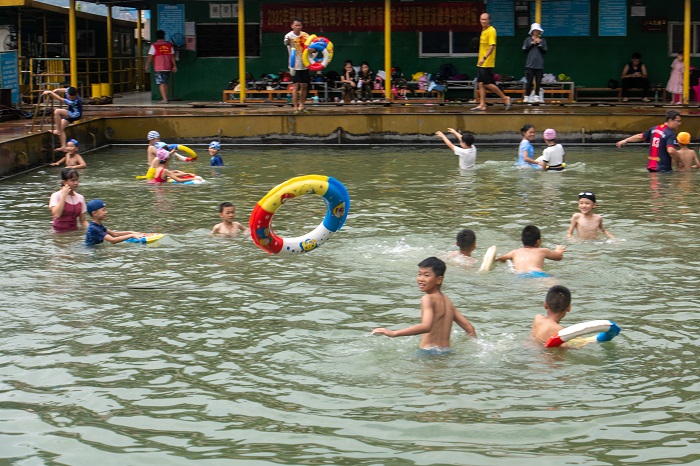 12、2022年7月17日，广西梧州市（桂江一桥边）游泳场内，孩子们在教练的指导下学习游泳技能。（何华文）