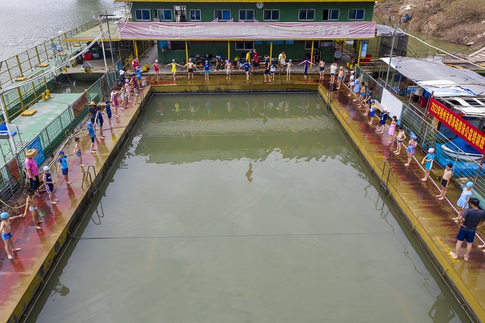 16、2022年7月17日，广西梧州市（桂江一桥边）游泳场内，孩子们在教练的指导下学习游泳技能。（何华文）