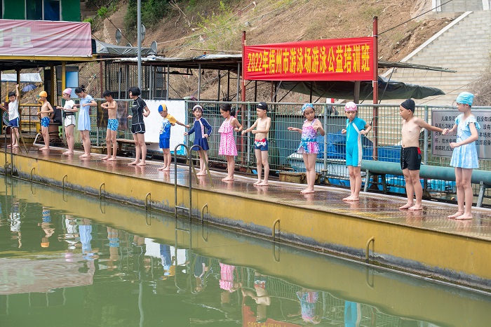 20、2022年7月17日，广西梧州市（桂江一桥边）游泳场内，孩子们在教练的指导下学习游泳技能。（何华文）
