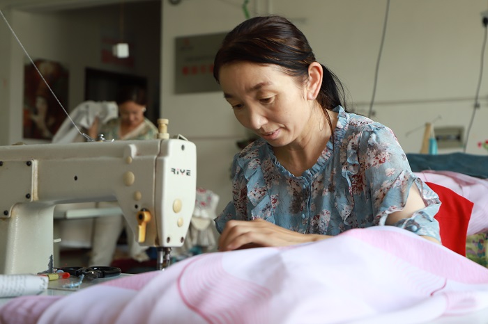 富蕴县阿克依额克民族刺绣专业合作社员工玛尼古丽·沙力合正在缝纫刺绣产品。