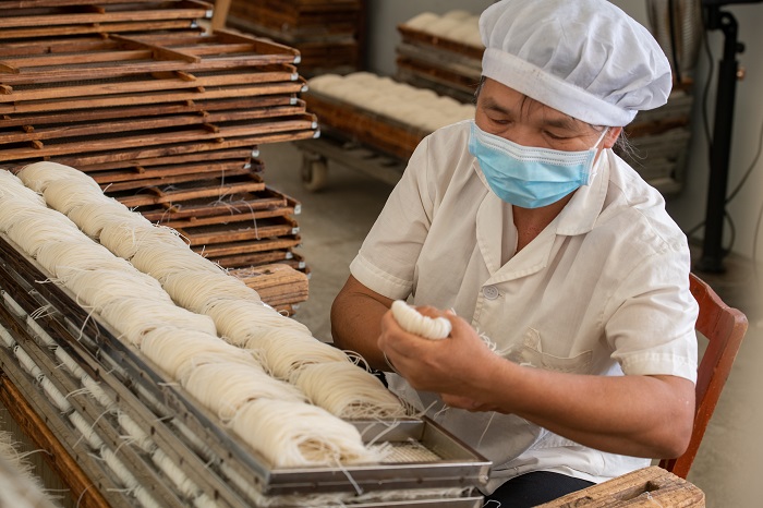 14、2022年9月22日，广西梧州市苍梧县京南米粉厂，工人在米粉出丝生产线上忙碌。（何华文）