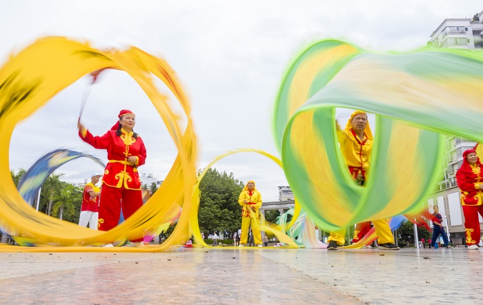 19、2022年9月30日，“彩带龙”爱好者在广西梧州市龙圩区世纪广场舞“彩带龙”，强身健体。（何华文）