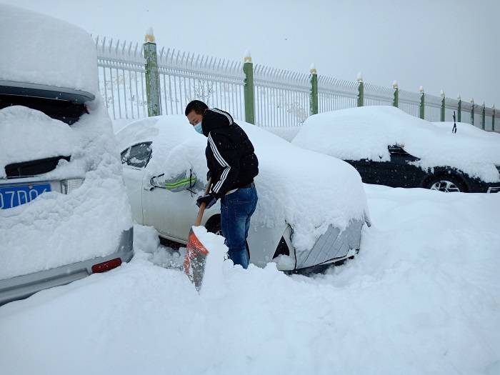 给汽车打扫积雪的居民，2022年11月23日摄于新疆阿勒泰地区阿勒泰市。