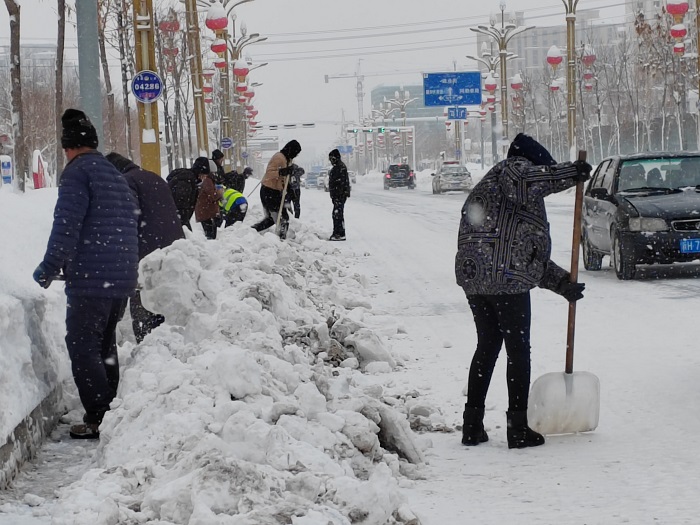 清理街道边角积雪的群众。