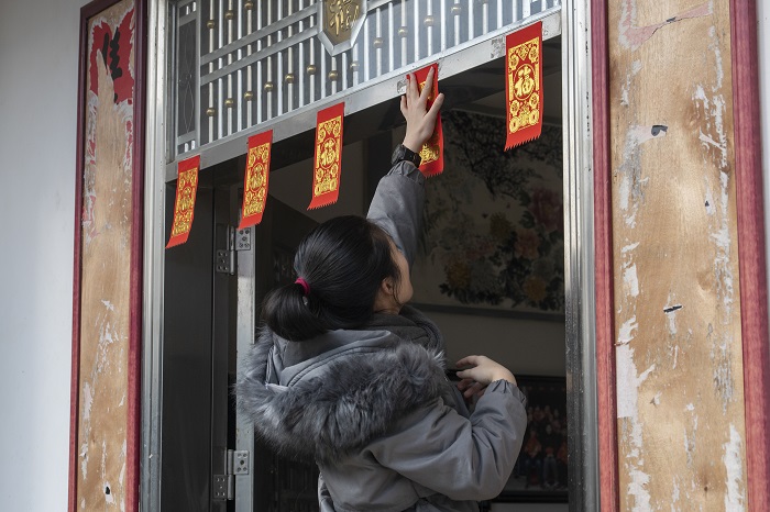 4、2023年1月20日，广西梧州市万秀区夏郢镇古藤村的村民沿袭传统的过年风俗，在自家门头贴春联，喜迎新年。（何华文）