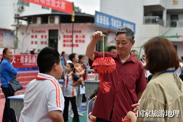 2023年4月20日，在贵州省从江县丙妹镇中心小学劳动技能大赛上，评委老师在点评学生制作灯笼作品。