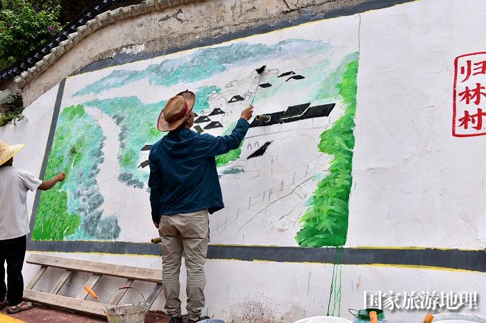 2023年5月27日，美术家协会会员在贵州省从江县丙梅街道月亮湾彩绘“文化墙”。