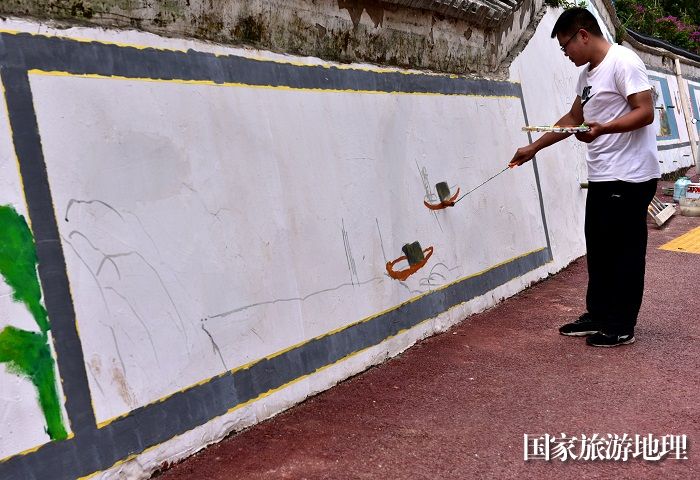 2023年5月27日，美术家协会会员在贵州省从江县丙梅街道月亮湾彩绘“文化墙”。2