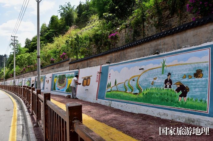 2023年5月27日，美术家协会会员在贵州省从江县丙梅街道月亮湾彩绘“文化墙”。4