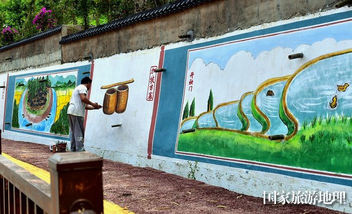 2023年5月27日，美术家协会会员在贵州省从江县丙梅街道月亮湾彩绘“文化墙”。5