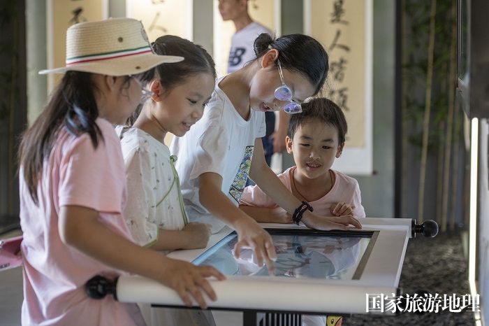 2、2023年7月27日，在广西梧州市明朝两广总督府家风馆，孩子在触摸屏体验阅读。（何华文）