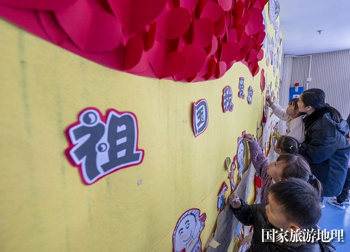5、2023年12月5日，检察官助理、法治副校长李绮雯在给小朋友讲解国徽、国旗、宪法等相关知识并在墙上绘画。（何华文）