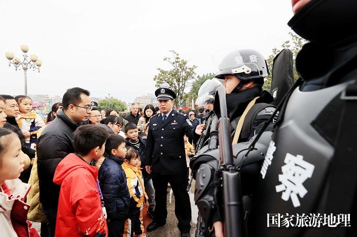 图9：1月7日，在广西柳州市融安县长安广场，公安民警向市民讲解警用枪支性能。（谭凯兴 摄）