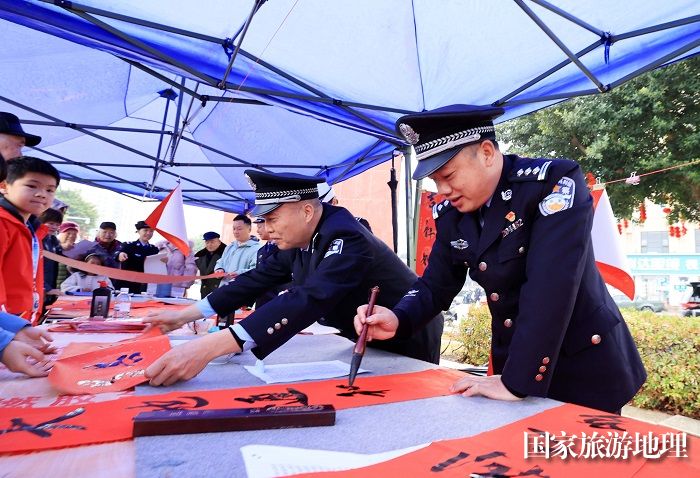 图18：1月7日，在广西柳州市融安县长安广场，公安民警在书写春联赠送市民。（谭凯兴 摄）