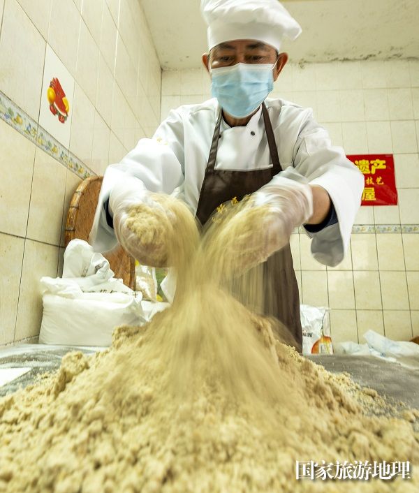 4、2024年1月19日，在广西非物质文化遗产梧州市龙圩万利饼屋猪油饼加工车间里，非遗传承人、猪油饼第五代传承人何家勇将猪油饼用料搅匀。（何华文）
