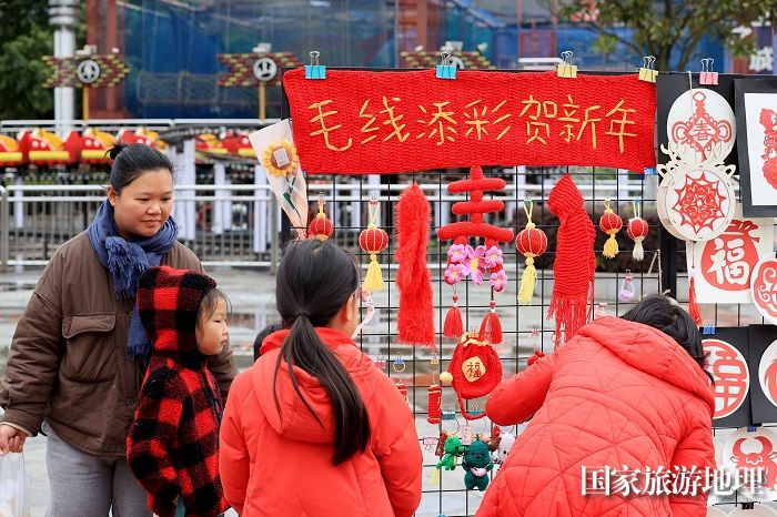 图3：1月20日，在广西柳州市融安县长安广场，市民在非遗集市上欣赏作品。（谭凯兴 摄）