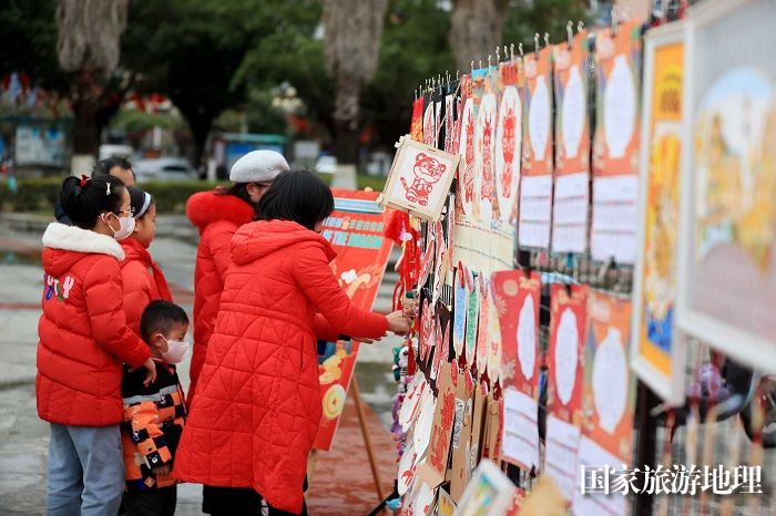 图5：1月20日，在广西柳州市融安县长安广场，市民在非遗集市上欣赏作品。（谭凯兴 摄）