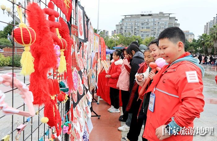 图7：1月20日，在广西柳州市融安县长安广场，学生在非遗集市上选购作品。（谭凯兴 摄）