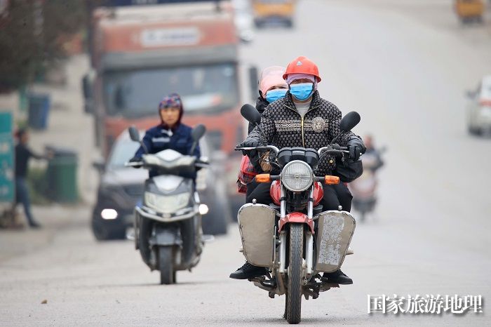 图1：1月26日，在国道209线广西柳州市融安县浮石镇路段，务工人员骑摩托车回家过年。（谭凯兴摄）